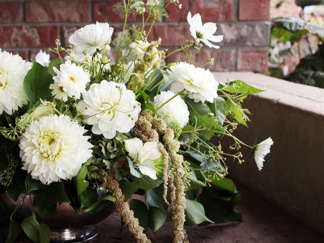Garden-style all white compote featuring white dahlias and other garden flowers in a vintage silver footed bowl
